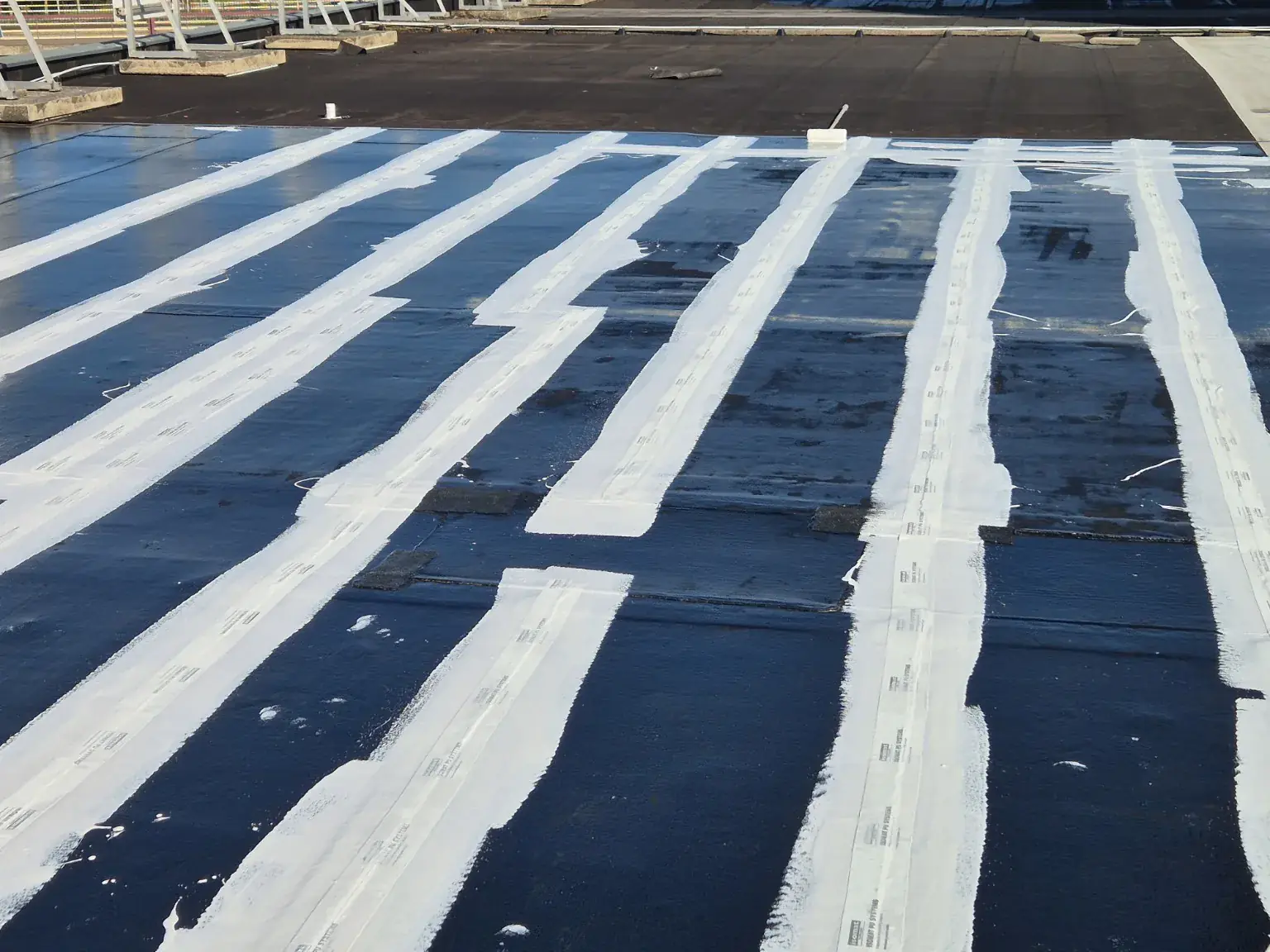 Geotextiel ingebed in coating over naden van een bitumen dak