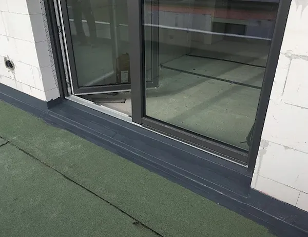 Deurkozijn en dorpel aangesloten op een plat dak met vloeibare afdichting